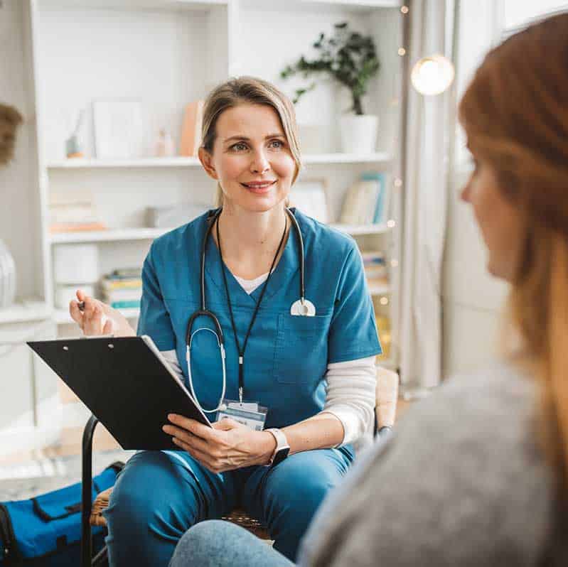 Female nurse taking notes during a client intake session.